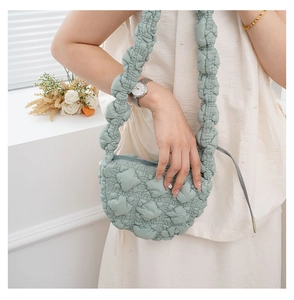 Detail of mint green quilted cloud bag featuring soft pleated texture and crescent shape
