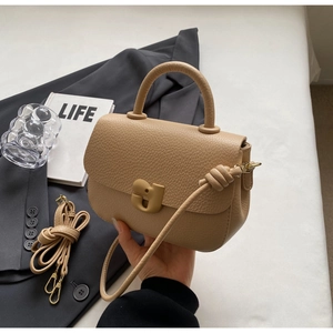 Détail du cuir grainé beige et de la boucle métallique design sur le sac selle