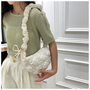 Detail of white quilted bubble shoulder bag with drawstring strap and ribbon charm
