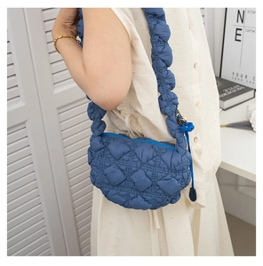Detail of the navy blue quilted dumpling bag featuring a wide padded shoulder strap