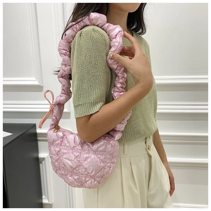 Close-up of pink quilted cloud bag with glossy satin finish and ruffled strap