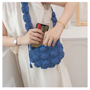 Detail view of blue quilted bubble bag showing spacious interior for phone and lipstick