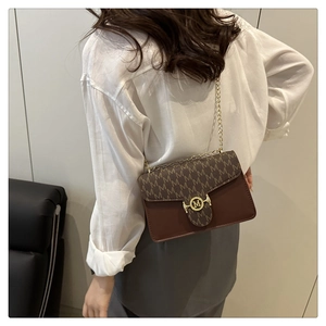 Detail of vintage brown monogram bag with golden chain and M buckle on a model