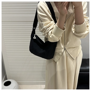Detail of black crescent shoulder bag with unique white triangular zipper puller