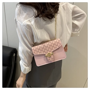 Detail of pink crossbody bag with M-pattern print and gold chain strap on model