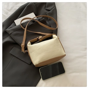 Detail of cream pleated fabric and brown leather small crossbody pillow bag texture