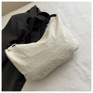 Detail view of the off-white nylon crescent bag with textured fabric and adjustable strap