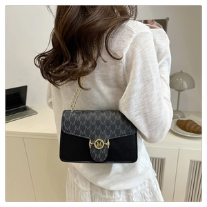 Detail of a black chain shoulder bag featuring a grey M-pattern and a round metal buckle