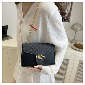 Detail showing the golden 'M' metal clasp and chain on black shoulder bag with logo pattern