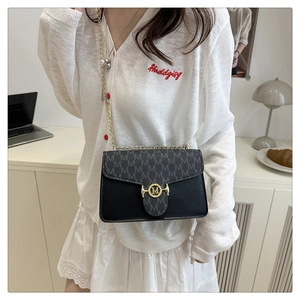 Detail of a chic chain shoulder bag with M pattern flap and gold logo on a model