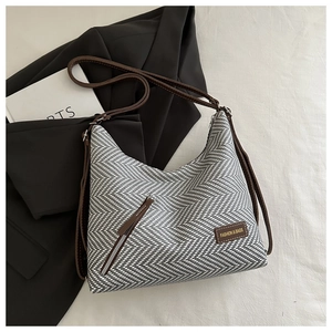 Detalle de bolso hobo tejido con correa de cuero marrón y bolsillo decorativo con cremallera