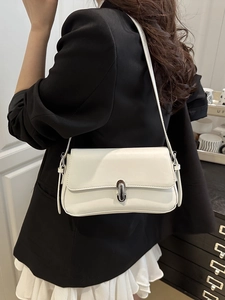 Minimalist white leather underarm bag with silver oval clasp shown on shoulder