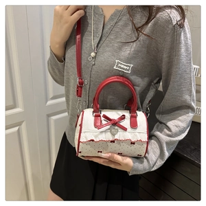 Detailed shot of red polka dot Boston bag with bow decoration and silver heart charm
