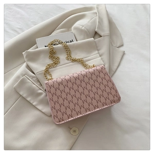 Close-up of pink shoulder bag with M letter monogram print and gold chain strap