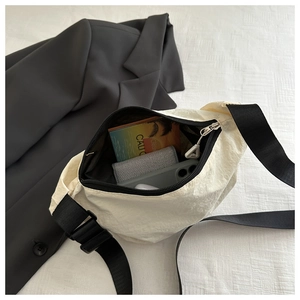 Top-down view of cream nylon crossbody bag showing spacious interior with wallet and phone