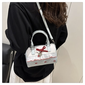 Détail du sac Boston bleu à pois avec nœud et breloque cœur porté par un mannequin