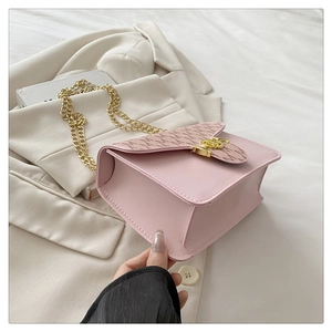 Detail of pink shoulder bag featuring gold chain strap and M-patterned flap