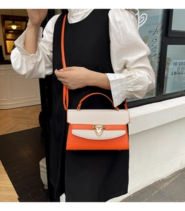 Dettaglio di una borsa in PU arancione acceso e tessuto beige con fibbia dorata e tracolla