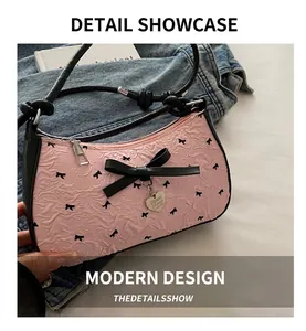 Close-up of pink textured fabric underarm bag with black bows and heart pendant