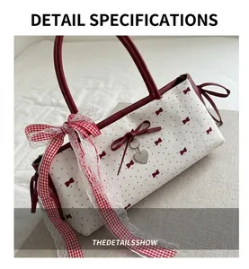 Close-up of red leather piping, polka dot fabric, and heart pendant on the bow bag