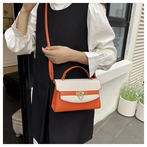 Detail of the orange and beige woven crossbody bag with gold rivet buckle and chain