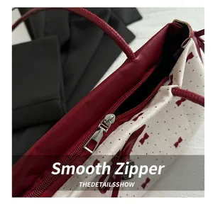 Detailed macro view of smooth silver metal zipper and red bow dot print fabric on handbag