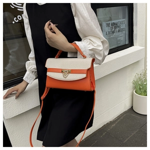 Detail of orange and cream leather handbag with woven texture and gold chain clasp
