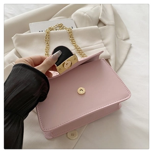 Detail view of pink flap bag with golden moon buckle and thick metal chain strap