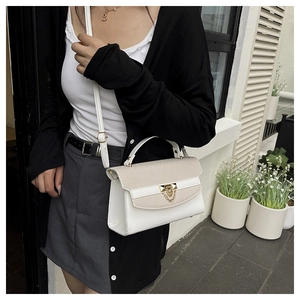 Detail of a white leather handbag featuring beige woven texture and gold triangular lock