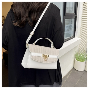 Detail view of a white crossbody bag with khaki woven texture on model in street style