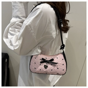 Détail du sac croissant rose avec texture florale et grand nœud noir avec pendentif cœur