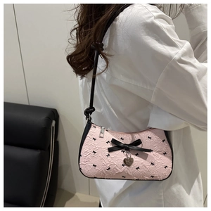 Détail du sac rose gaufré avec nœuds noirs et pendentif cœur sur bandoulière noire