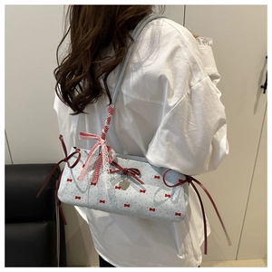 Detail of blue canvas bag featuring red bow prints, lace edges and heart pendant
