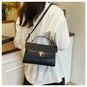 Detail of black crossbody bag with gold hardware lock and stylish textured leather flap