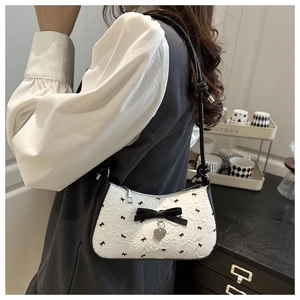 Détail du sac hobo en jacquard blanc avec nœuds noirs et breloque cœur argentée