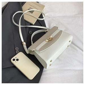 Detailed top view of a beige woven and white faux leather crossbody bag with gold buckle