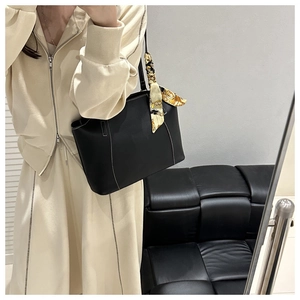 Detail of black leather tote bag with white contrast stitching and yellow silk scarf