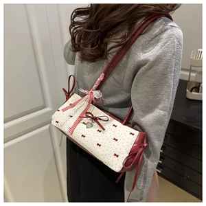 Detailed macro view of the bow and heart pendant on the sweet polka dot shoulder bag
