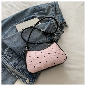 Detail of pink crescent underarm bag with black bow print and stylish knot strap design
