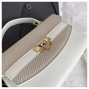 Detail of white leather and beige woven fabric on woman handbag with gold lock