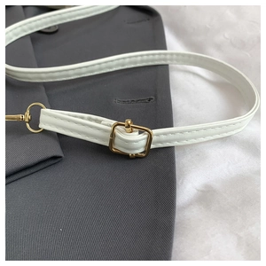 Detail of adjustable white leather strap with premium gold hardware and fine stitching
