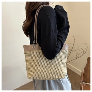 Detail of summer straw tote bag with faux leather trim and silver metal eyelets