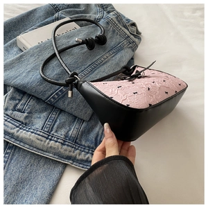 Detail showing pink jacquard fabric with black bows and knotted rope strap of the shoulder bag