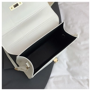 Top view of open white leather handbag showing black interior lining and gold hardware