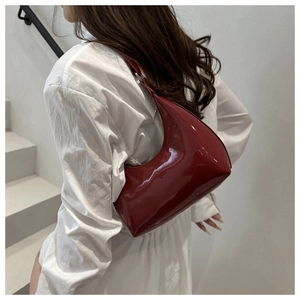 Elegante borsa hobo in vernice bordeaux indossata da una modella su scale bianche