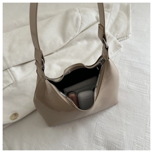 Close-up of beige patent leather hobo bag showing interior capacity and glossy finish