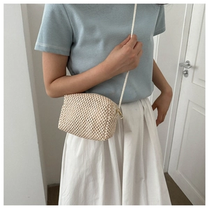 Close-up of beige hand-woven crossbody bag with golden zipper and rope strap detail