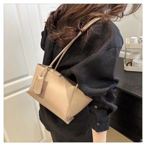 Sac à bandoulière minimaliste en cuir beige porté par un mannequin, forme rectangulaire