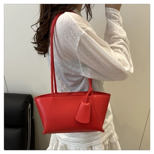 Détail du sac cabas en cuir rouge avec coutures incurvées et doubles fines bandoulières