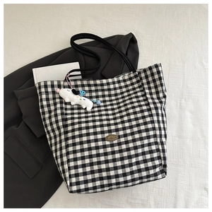 Gros plan du sac cabas à carreaux noir et blanc avec un joli pendentif peluche chiot